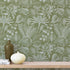 Floral green wallpaper with a wooden shelf and decorative items in the foreground