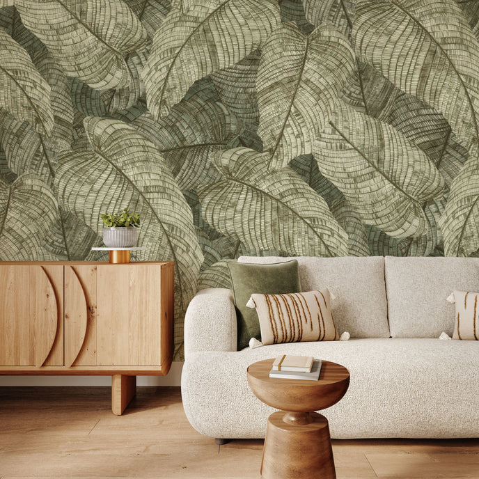 In a seating room there is a vintage botanical wallpaper featuring overlapping fern leaves in soft sage and olive green tones, creating a richly textured nature inspired pattern. 