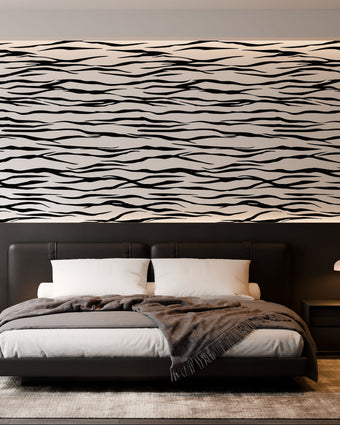 A modern bedroom featuring a horizontal zebra stripe wallpaper with a seamless repeat, featuring flowing black stripes on a white background in a bold animal-inspired pattern. With a low bed with grey bedding and dark bedside tables.

