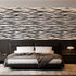 A modern bedroom featuring a horizontal zebra stripe wallpaper with a seamless repeat, featuring flowing black stripes on a white background in a bold animal-inspired pattern. With a low bed with grey bedding and dark bedside tables.

