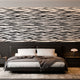 A modern bedroom featuring a horizontal zebra stripe wallpaper with a seamless repeat, featuring flowing black stripes on a white background in a bold animal-inspired pattern. With a low bed with grey bedding and dark bedside tables.

