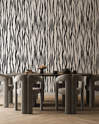 A dining set featuring a rectangular wooden table and six curved grey chairs, set against a bold black and white vertical zebra stripe wallpaper with a seamless repeat, featuring flowing black stripes on a white background in a bold animal inspired pattern, and light wood herringbone flooring.

