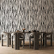 A dining set featuring a rectangular wooden table and six curved grey chairs, set against a bold black and white vertical zebra stripe wallpaper with a seamless repeat, featuring flowing black stripes on a white background in a bold animal inspired pattern, and light wood herringbone flooring.

